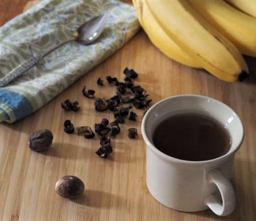 photo of banana peel tea in cup with dried banana peels and whole nutmegs