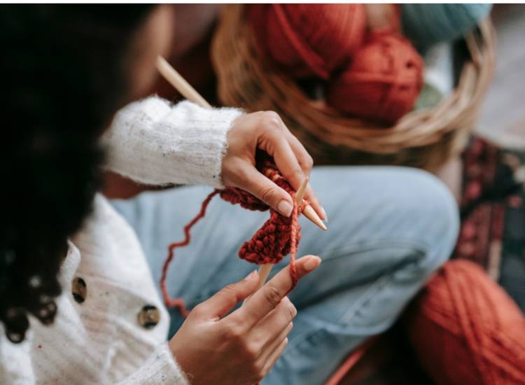 photo of woman knitting with red yarn
