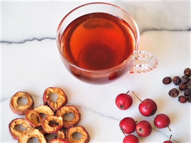 photo of tea made from hawthorn berries with berries on marble background