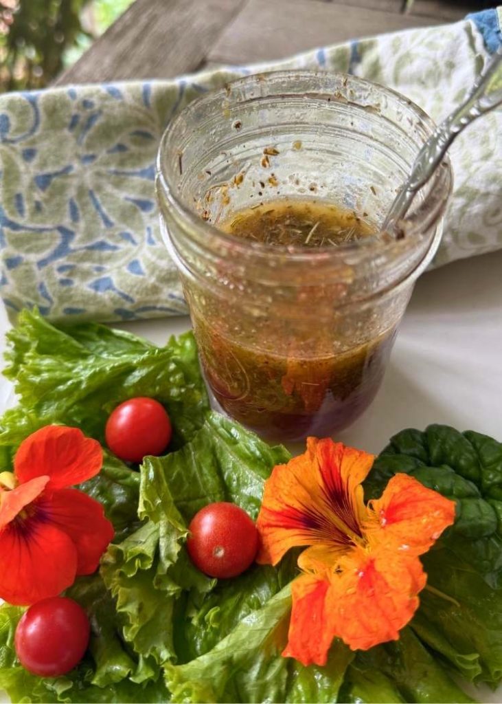 photo of herb vinaigrette recipe in jar surrounded with lettuce and nasturtiums